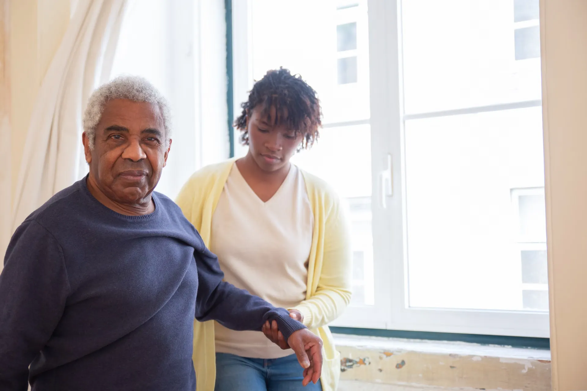 Caregiver sitting with a smiling senior man at home, caregiver career resources and CNA exam prep